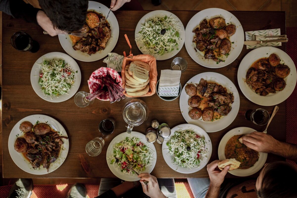 Overhead table set with shared dishes, salads, and bread.